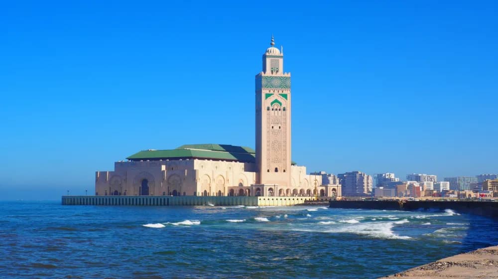 Mosquée Hassan II en bord de mer à Casablanca, avec la ville moderne en arrière-plan